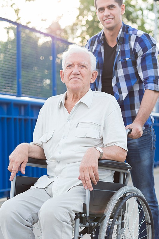 גבר מלווה אדם מבוגר על כיסא גלגלים
